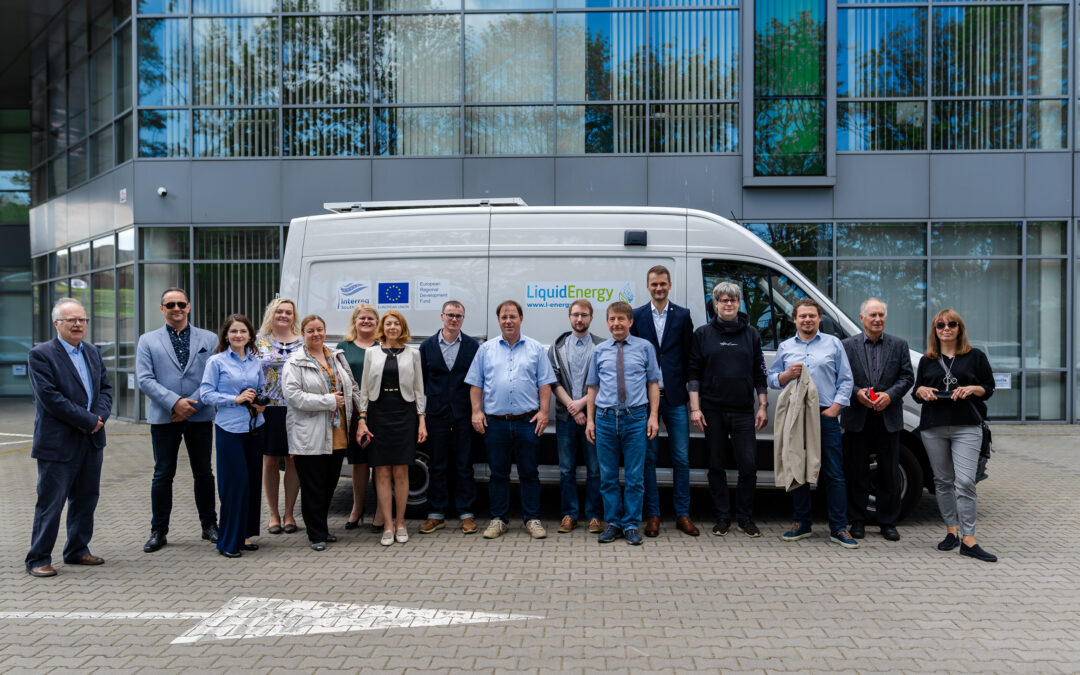 The photo presents the partners of the Liquid Energy project in front of the mobile LNG and bioLNG refueling station, which stands in the parking lot of the Gdańsk Science and Technology Park.