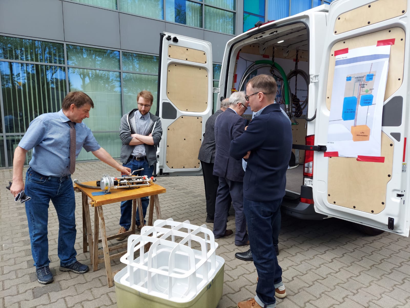 The photo presents the partners of the Liquid Energy project in front of the mobile LNG and bioLNG refueling station, which stands in the parking lot of the Gdańsk Science and Technology Park.